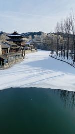 Scenic view of lake by building against sky during winter