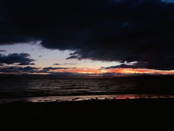 Scenic view of sea against dramatic sky during sunset