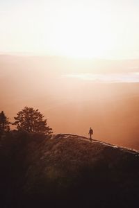 High angle view of silhouette man standing on mountain against sky