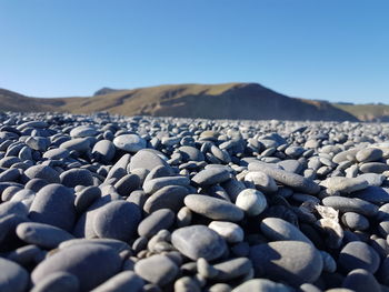 Surface level of pebble beach against clear sky