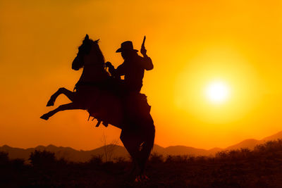 Silhouette men on field against sky during sunset