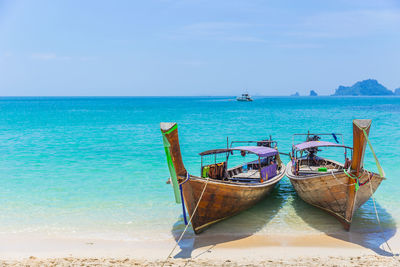 Fishing boats moored on sea against sky