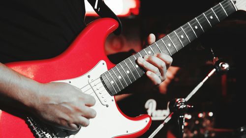 Midsection of man holding guitar