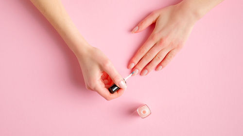 High angle view of woman hand over pink background