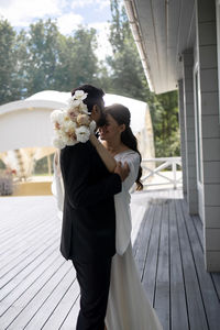Side view of bride and bridegroom holding bouquet
