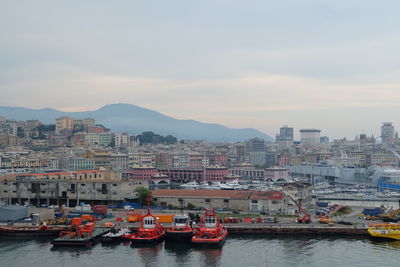 Boats moored on river against cityscape during sunset