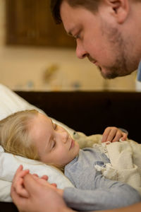 Dad strokes his sick child, looks with care, tenderness and love, holds the hand. the concept of