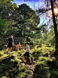Low angle view of family hiking on grassy mountain during sunny day