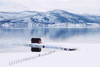 House on snow at lakeshore against sky