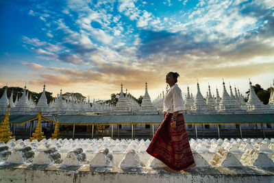 Rear view of woman standing on shore against sky