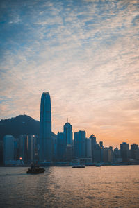 Sea by buildings against sky during sunset