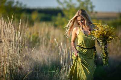 Portrait of young woman standing against plants