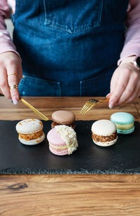 A pasta dessert lies on a concrete black stand, and a girl cuts sweets with a knife and fork