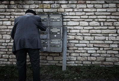 Rear view of man standing against stone wall