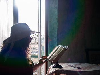 Woman reading book on table at home