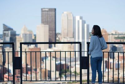 Rear view of woman standing against railing in city