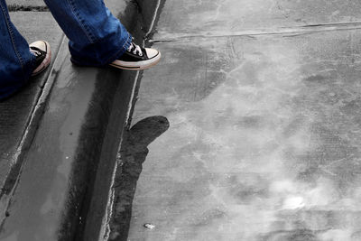 Low section of man standing by puddle on footpath