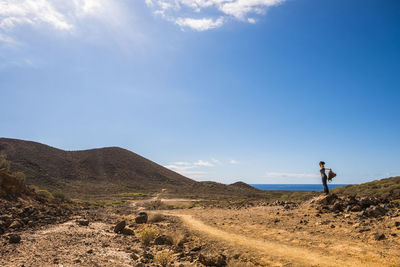 Woman standing on rock against sky