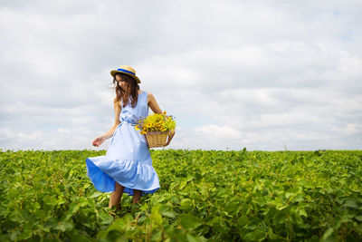 Full length of woman standing amidst field against sky