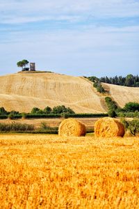 Hay bales on field against sky, tuscany, italy