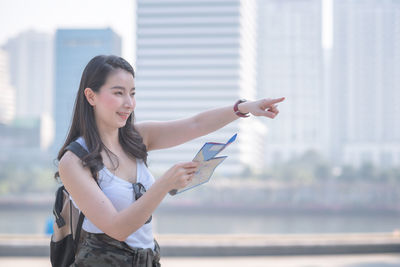 Young woman with arms raised standing in city