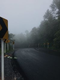 Empty road by trees against sky