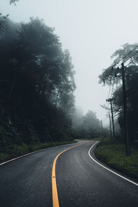 Road by trees against sky