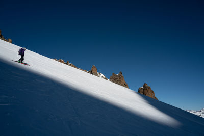 People on snowcapped mountain against blue sky