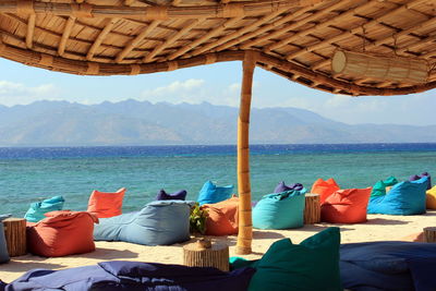 Chairs on beach by sea against sky