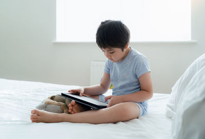 Boy using laptop while lying on bed at home