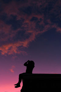 Silhouette man and woman standing against orange sky