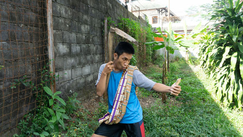 Young man smiling while standing against plants