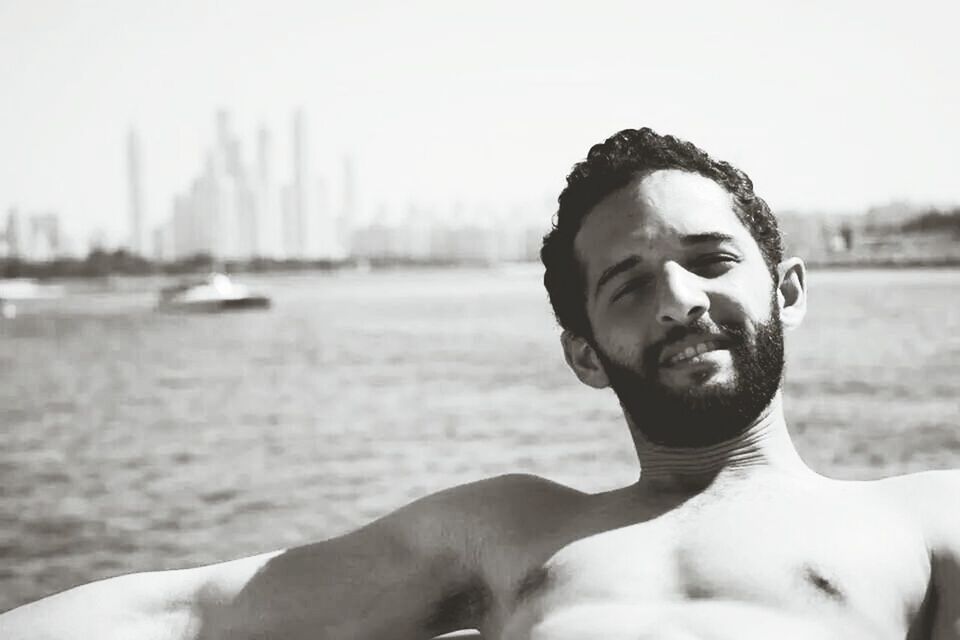 focus on foreground, lifestyles, water, person, headshot, young adult, leisure activity, young men, sunglasses, portrait, looking at camera, sea, head and shoulders, close-up, front view, sky, outdoors, beach