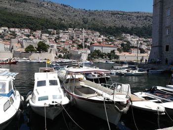 Sailboats moored in harbor by buildings in city