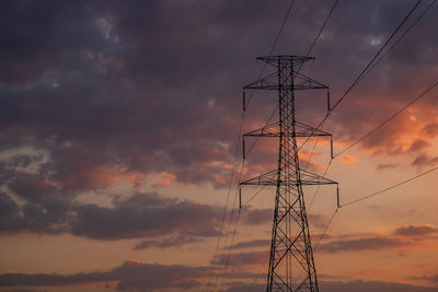 Low angle view of silhouette electricity pylon against sky during sunset