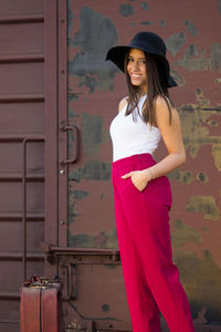 Portrait of a smiling young woman standing against wall