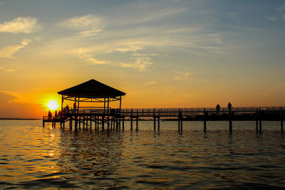 Pier over sea against sky during sunset