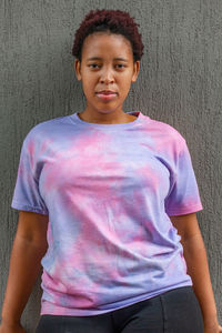 Portrait of teenage girl standing against pink wall