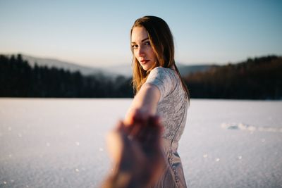 Portrait of young woman standing by tree against sky during sunset