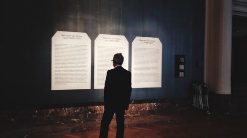 Rear view of man standing against wall at home