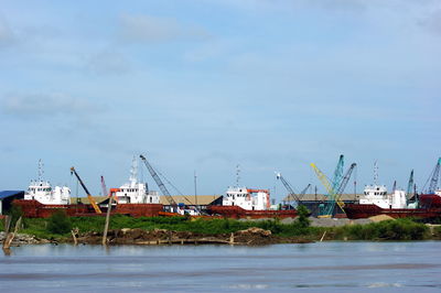 Cranes at harbor against sky