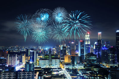 Firework display over illuminated buildings in city at night