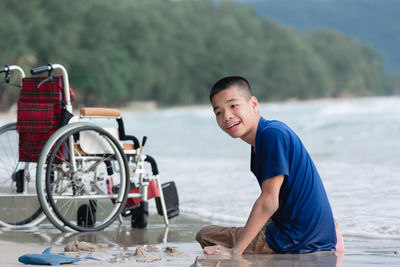 Side view of handicapped boy sitting on seashore