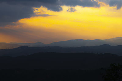 Scenic view of silhouette mountains against orange sky