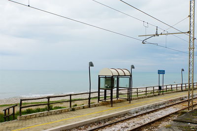 Railroad track by sea against sky