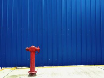 Close-up of fire hydrant on footpath against blue wall