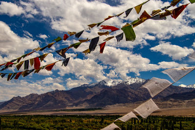 Multi colored flags hanging on mountain against sky