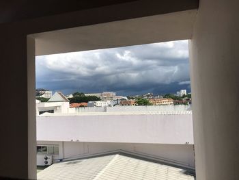 Buildings in city against sky seen through window