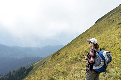 Young woman in cap with hiking backpack looking at mountain view of aibga ridge active lifestyle
