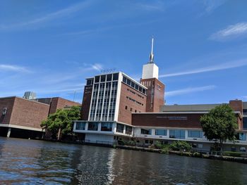 Buildings by river against sky in city